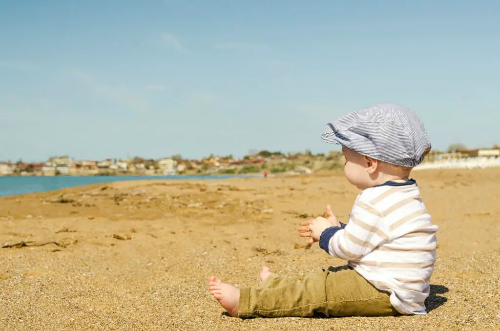sitting toddler on seashore at daytime